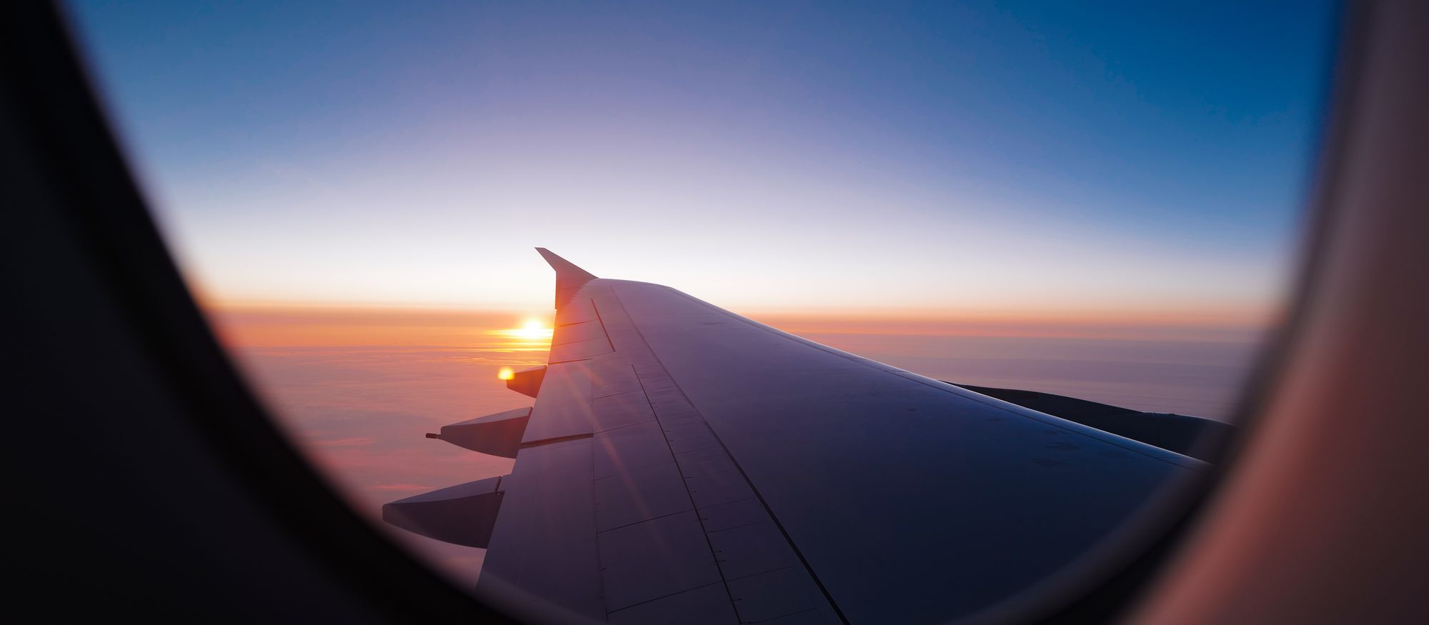 The last light of sunset beyond an aircraft wing, seen through the window.