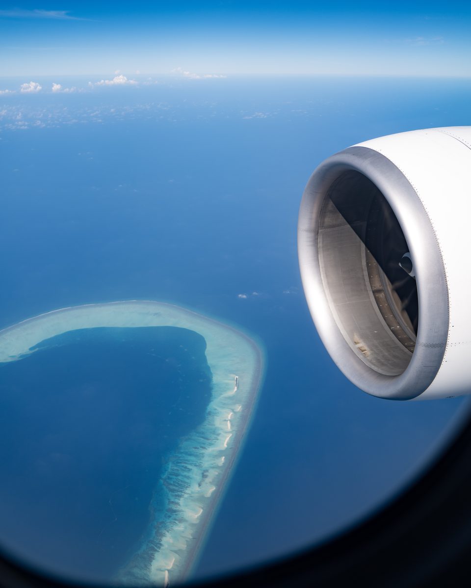 An aircraft engine above a ring of reef curving through deep blue water.